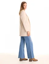 Blazer de tejido soft color beige, con silueta relajada y corte largo. Presenta cuello con solapas muesca, frente abierto sin botones y dos bolsillos de parche frontales.