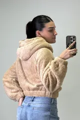Canguro de peluche con capucha, cierre frontal completo y bolsillos laterales. Diseño de corte corto y textura suave.