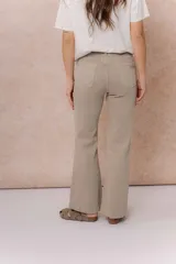 Pantalón de jean color arena, de corte flare con pierna levemente acampanada y tiro medio. Cuenta con cierre frontal, botón, pasacintos y bolsillos funcionales.