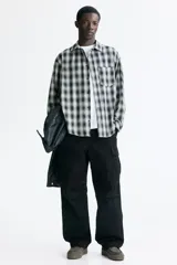 Camisa de corte relajado, confeccionada en mezcla de algodón suave con diseño a cuadros difuminados en tonos negro y blanco. Cuenta con cuello inglés, cierre frontal de botones, bolsillo en el pecho y mangas largas con puños abotonados.