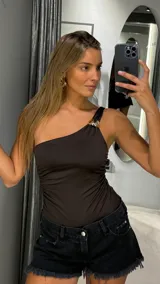 Body de un solo hombro color chocolate, con detalle de aplique metálico dorado en el tirante y diseño ajustado al cuerpo.