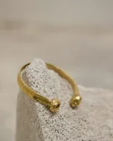 Brazalete rígido abierto de metal color plateado, con terminaciones en forma de herradura.