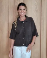 Cardigan de punto color marrón chocolate, con cuello camisero, cierre frontal de botones y mangas cortas. Presenta dos bolsillos frontales y terminaciones en tejido acanalado.