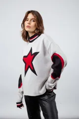 Sweater tejido en lana con viscosa y poliéster, color gris claro, con diseño de estrella roja en el pecho y parches negros en los codos.