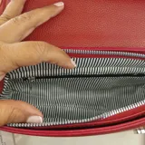 Cartera tipo bandolera de tamaño pequeño, color rojo, con solapa frontal y letras doradas estampadas que dicen 'THE MINI BAG'. Incluye una correa de tela ajustable y herrajes metálicos.