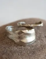 Brazalete rígido plateado con textura irregular.