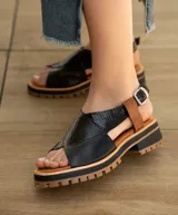 Sandalia de cuero vacuno color negro, con suela de goma deportiva, hebilla al tobillo y horma ancha.