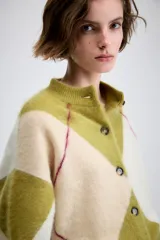 Chaqueta de punto con diseño de rombos en tonos verde oliva y crema, con cuello redondo, cierre frontal de botones y mangas largas con puños ajustados.