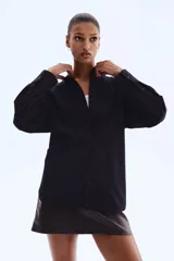 Camisa de manga larga, color negro o azul muy oscuro, con finas rayas verticales en tono más claro. Presenta cuello clásico, cierre frontal de botones y corte holgado con bajo redondeado y aberturas laterales.