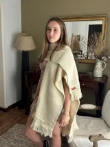 Ruana tejida en telar, hecha en pura lana de oveja Merino fino. Diseño en color natural, guardas texturadas y terminación con flecos.
