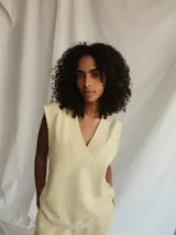 Chaleco color amarillo pálido con escote en V y sisas con terminación desflecada.