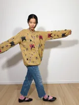 Sweater tejido color mostaza con cuello redondo y diseño bordado a mano con lana merino, con motivos de insectos de diversos colores.