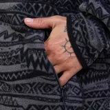 Canguro con cierre frontal completo y capucha, confeccionado en tejido polar con estampado geométrico tribal en tonos grises y negros. Cuenta con bolsillos laterales y puños elásticos.