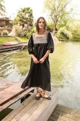 Túnica de lino color crudo con corte holgado y mangas abullonadas con elástico. Presenta una pechera frontal y trasera con estampado étnico en tonos terracota y amarillo.