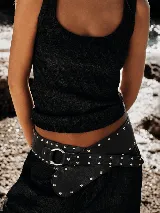 Faja de cuero negro con diseño ancho, decorada con múltiples tachas metálicas plateadas y cierre mediante hebilla de argolla metálica.