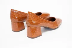 Zapato de cuero color marrón con textura de cocodrilo, de tacón cuadrado y puntera redondeada.