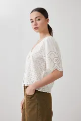 Blusa negra de broderie con escote en V y lazos para atar en el frente. Tiene mangas cortas con terminación de puntilla. 