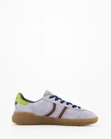 Championes Coolway modelo Kiro Lavender Rush, confeccionados en gamuza de color lila con detalles en marrón, rosa, verde lima y suela de goma marrón translúcida. Presentan diseño retro con doble franja lateral ondulada y cordones oscuros.