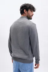Buzo de tejido de punto en color gris, con cuello alto y cierre frontal parcial. Presenta puños y ruedo acanalados.