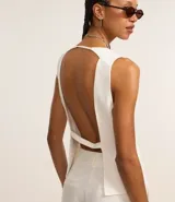 Chaleco de vestir color blanco hueso, con escote en V, cierre frontal con botones y espalda abierta. Corte sastrero.