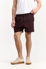 Short de baño de color marrón con textura en relieve, cintura elástica con cordón ajustable, bolsillos laterales y bolsillo trasero con detalle de la marca.