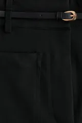 Pantalón de tiro alto y piernas acampanadas color negro, con bolsillos tipo parche en el frente, pliegues planchados al frente y en la espalda, y un cinturón fino incluido.
