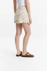 Falda corta tipo pareo con diseño envolvente y nudo frontal. Presenta un estampado marmolado en tonos tierra sobre fondo claro.