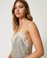 Vestido midi plateado de tirantes finos, cubierto completamente de lentejuelas. Presenta un escote en V ribeteado con encaje blanco y un sutil estampado floral en tonos pastel en la parte inferior.