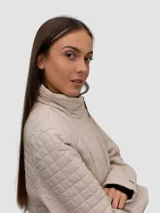 Campera acolchada de diseño ligero con cuello alto, cierre frontal de cremallera y bolsillos laterales. Presenta un patrón de costuras cuadradas y detalles distintivos de la marca.