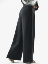 Pantalón deportivo Adidas de corte holgado y pernera ancha, color negro, con cintura elástica y cordón ajustable. Cuenta con bolsillos laterales y el logo del trifolio bordado en la pierna izquierda.