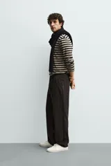 Pantalón de corte recto confeccionado en tejido elástico, con cintura elástica, pliegues frontales, bolsillos laterales y bolsillos traseros de vivo con botón.
