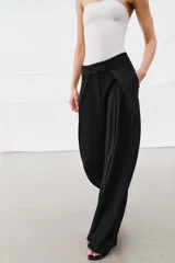 Pantalón de tiro medio de la ZW Collection, color negro, con diseño de pierna ancha (wide leg) y detalle de pliegues en la parte delantera. Cuenta con bolsillos laterales ocultos y cierre frontal con cremallera, botón y ganchos metálicos.