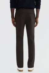 Pantalón sastrero de corte slim fit en color marrón, con pliegues frontales, cierre de botón y trabillas para cinturón.