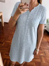 Camisón de manga corta en color celeste con estampado floral pequeño. Presenta un cuello con tapeta de botones y un bolsillo frontal en el pecho.