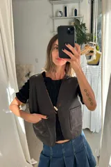 Chaleco reversible de cuero genuino color marrón oscuro, con cierre frontal mediante un botón tipo toggle y bolsillos frontales aplicados.