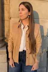 Camisa de cuero ovino color beige claro, estilo western, con canesú en los hombros en gamuza de tono similar. Presenta costuras contrastantes y cierre frontal con broches. Posee bolsillos laterales.