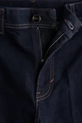 Jean wide leg de tiro alto en denim azul oscuro con costuras en tono contraste, trabillas para cinto y cierre frontal con botón metálico.