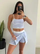 Conjunto deportivo lila compuesto por un top corto con tirantes finos y una minifalda con short incorporado.