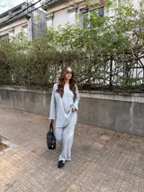 Conjunto de dos piezas de lanilla en color gris melange, compuesto por un buzo oversize de manga larga con aberturas laterales y un pantalón largo de corte recto y holgado.