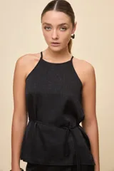 Top negro de calce relajado y textura satinada, con escote halter y lazo fino para ajustar en la cintura.