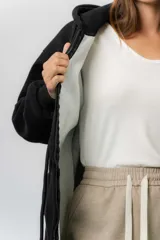 Campera deportiva con capucha de corte oversize, confeccionada en tejido suave con interior forrado en piel sintética. Presenta cierre frontal completo, bolsillos laterales y capucha amplia con cordones largos ajustables.