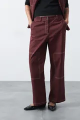 Pantalón de corte recto y tiro medio, confeccionado en algodón con elastano. Presenta costuras a contratono en color blanco que resaltan los recortes delanteros y el diseño de la prenda, aportando un estilo utilitario.