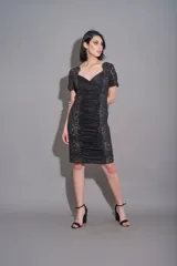 Vestido negro de corte recto, con cuello cruzado, mangas cortas de encaje con bordados y laterales de encaje con bordados.