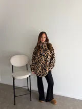 Buzo de peluche con estampado animal print en blanco y negro, cuello alto y cierre frontal con tirador personalizado.