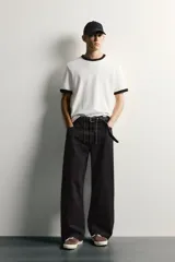 Pantalón barrel fit de mezclilla color verde militar, con efecto lavado, cinco bolsillos, cierre frontal con cremallera y botón, y detalle de pinzas en las rodillas.