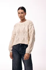 Sweater de tejido de punto grueso con diseño de rombos en relieve, cuello redondo y mangas largas amplias. Presenta una silueta relajada y holgada.