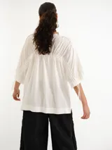 Remerón blanco de corte holgado, mangas cortas amplias y cuello bote con jareta.