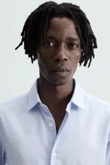 Camisa de corte regular fit en color celeste, con cuello italiano, manga larga con puños abotonados y cierre frontal de botones.