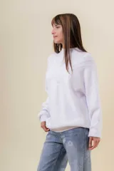 Sweater tejido de punto color blanco, con cuello alto y diseño en relieve tipo chevron en la parte frontal. Presenta un calce holgado con terminaciones acanaladas en puños y ruedo.