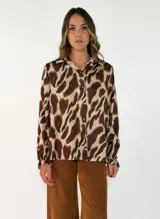 Camisa de manga larga con estampado animal print en tonos marrones y beige, cuello clásico y cierre frontal con botones. Presenta puños con elástico.